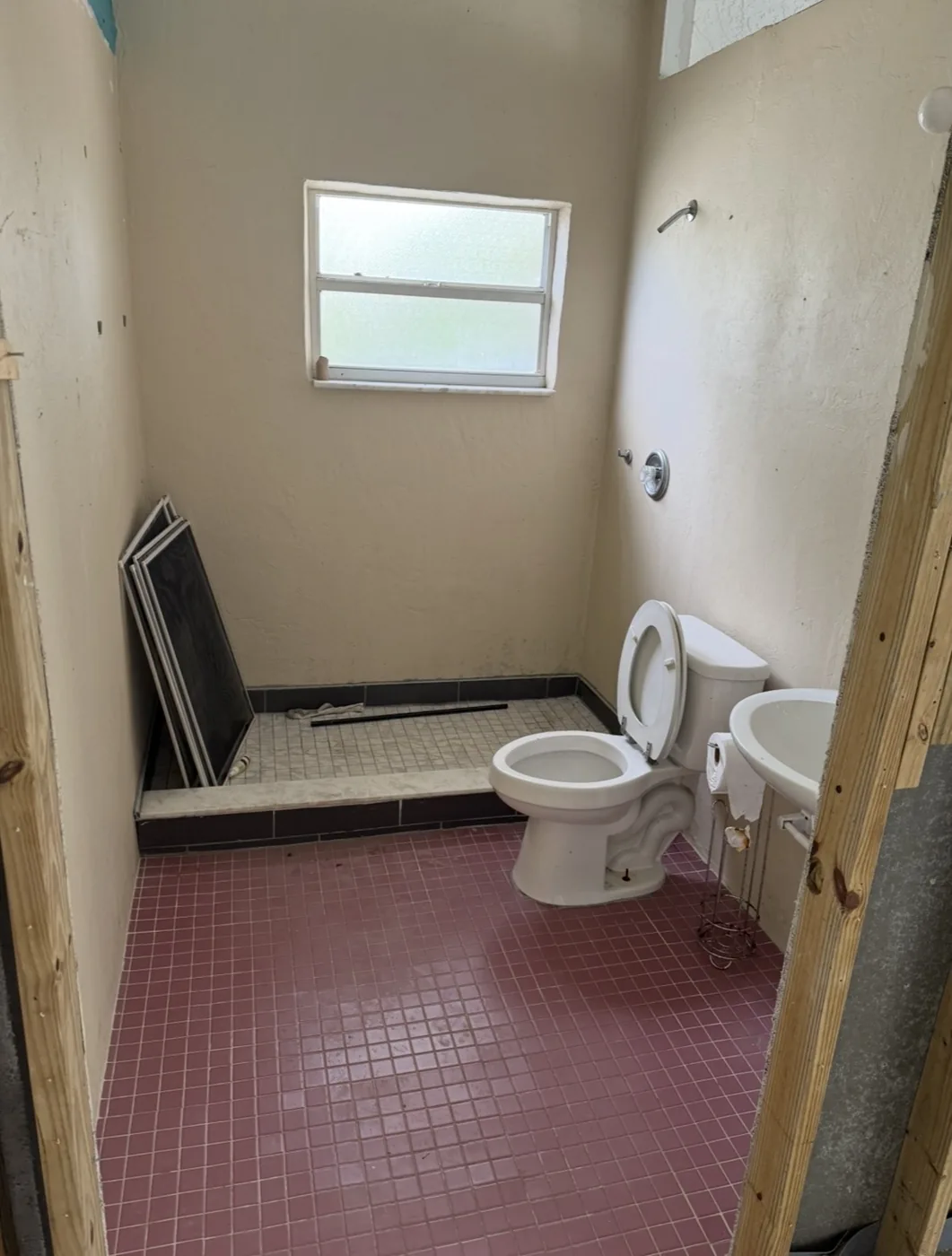 Bathroom before the upgrade, with worn cream walls and pink floor tile